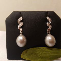 Zilveren oorbellen, hangend model. Krullend staafje naar onderen, bezet met zirconia stenen. Met daaronder grijze druppelvormige parel.